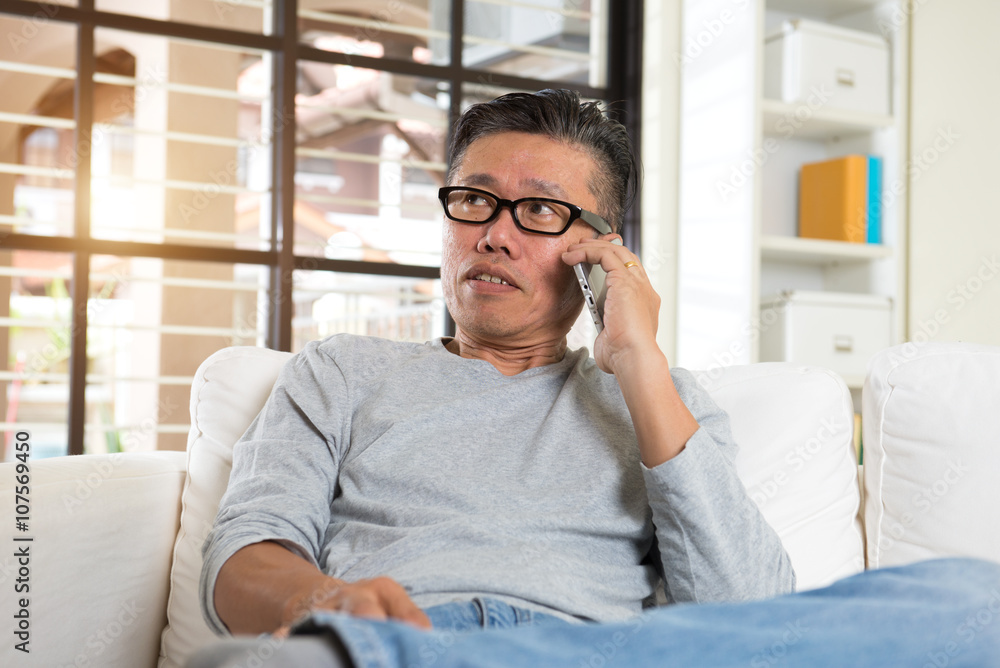 Happy asian senior man using the mobile phone at home Happy asian senior man using the mobile phone at home