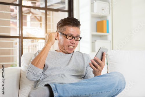 Happy asian senior man using the mobile phone at home