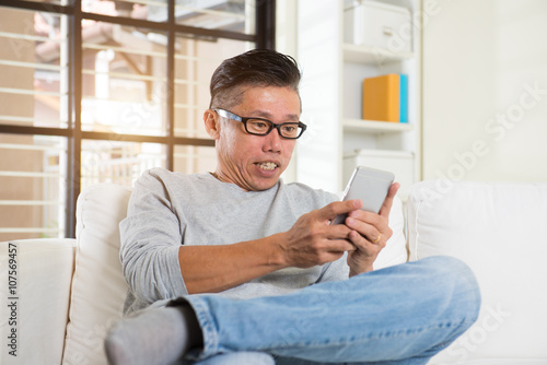 Happy asian senior man using the mobile phone at home