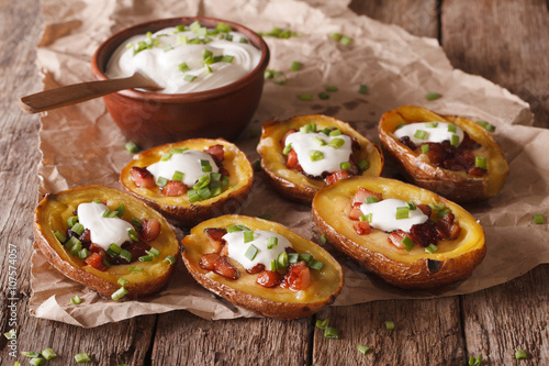 Rustic potato skins with cheese, bacon and sour cream close-up 