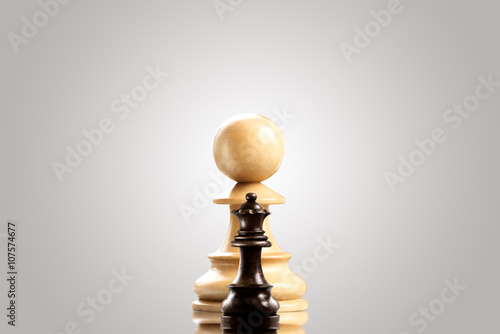 Ambitious pawn   Leadership and bravery concept  huge white wooden pawn staying against a small black queen.