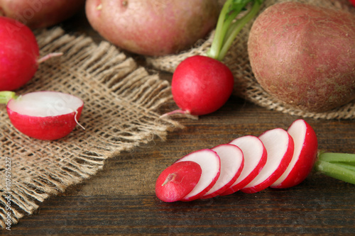 red potatoes with chopped radishes on sackcloth on wooden brown background