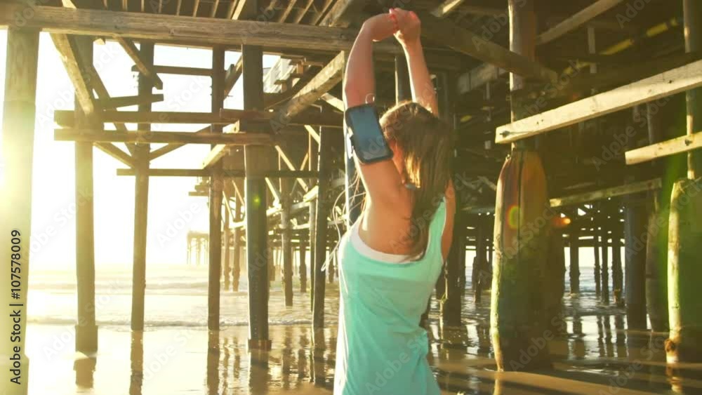 Woman Runner Stretching on Beach Under Pier at Sunset. Fitness Workout Healthy Outdoor Lifestyle. SLOW MOTION Woman Runner Stretching on Beach Under Pier at Sunset. Fitness Workout Healthy Outdoor Lifestyle. SLOW MOTION