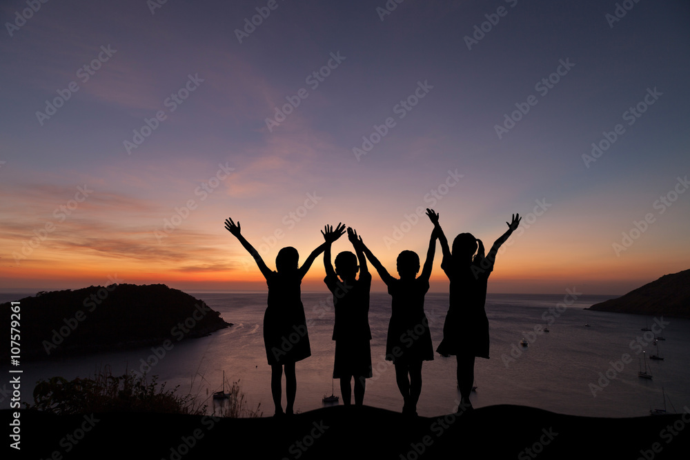 silhouette Group of happy children standing with open arms at su