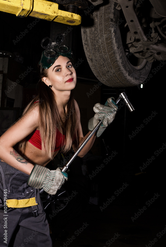 Beautiful young female mechanic inspecting car in auto repair shop