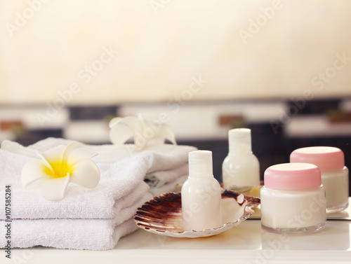 White towels with cream and tropical flower on a shelf in bathroom