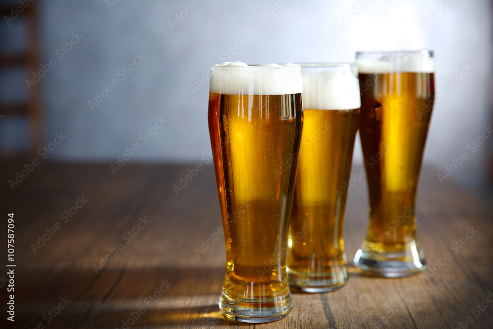 Three glasses of light beer on wooden table Three glasses of light beer on wooden table