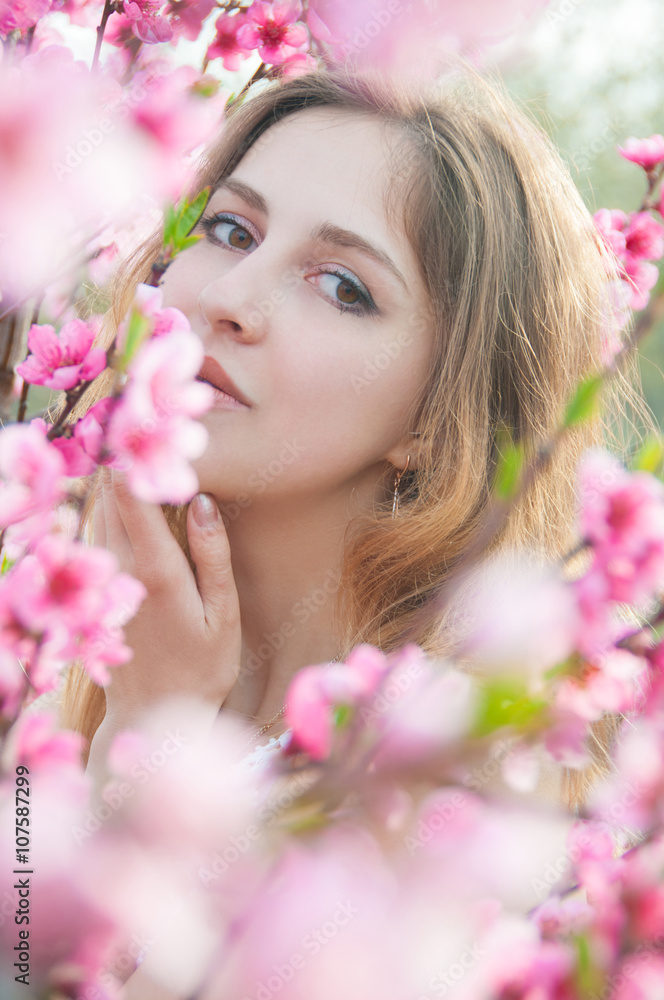 Portrait of young woman in the flowered garden in the springtime. Tender and beautiful posing. Portrait of young woman in the flowered garden in the springtime. Tender and beautiful posing.