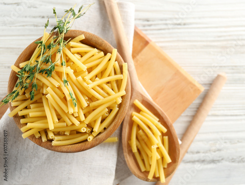 Raw pasta in bowl on wooden table closeup photo