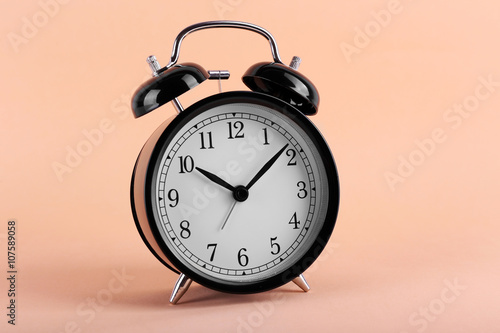Black retro alarm clock on peach background