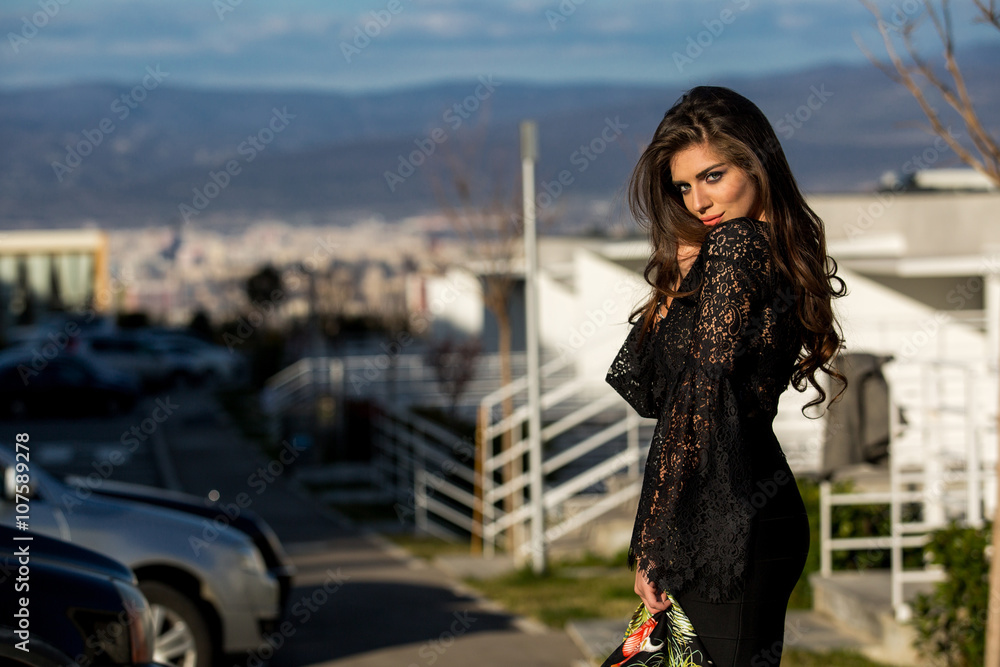 Beautiful girl model brunette in black dress on the street