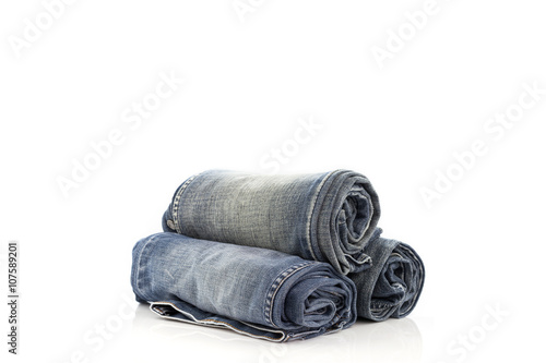  Stack of rolled  blue jeans on white background.