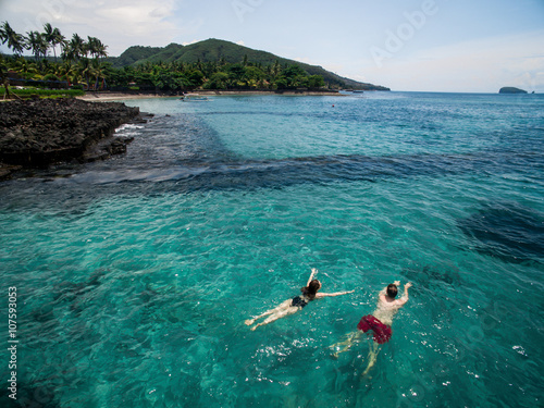 Romantic couple swimming in blue water of Indian ocean holding hands while honeymoon vacation