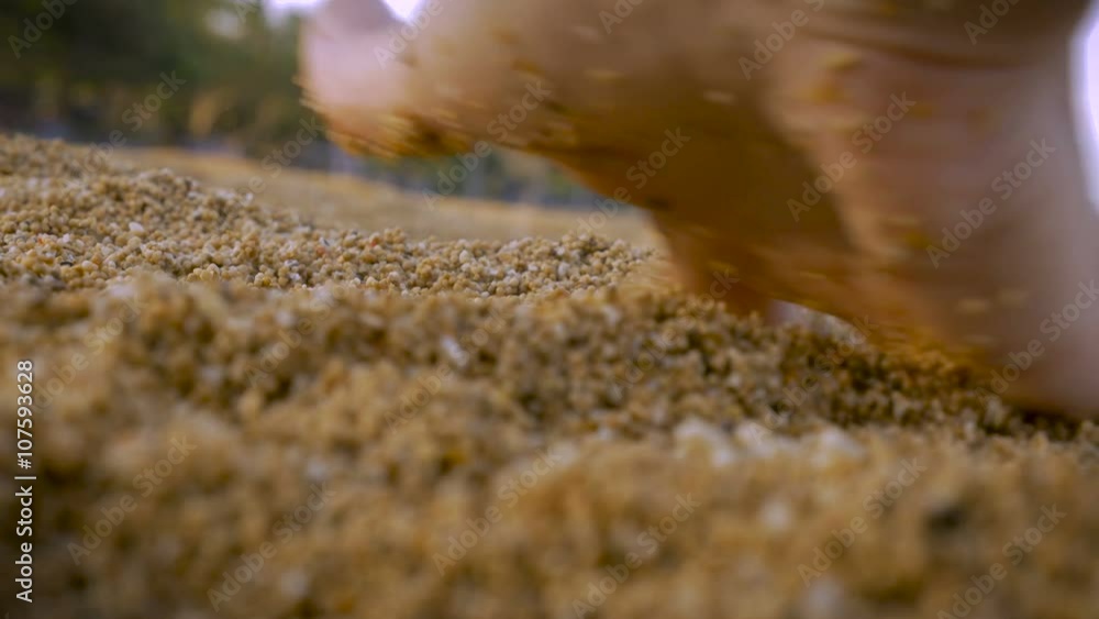 Close up of a hand running fingers through course sand on the beach
