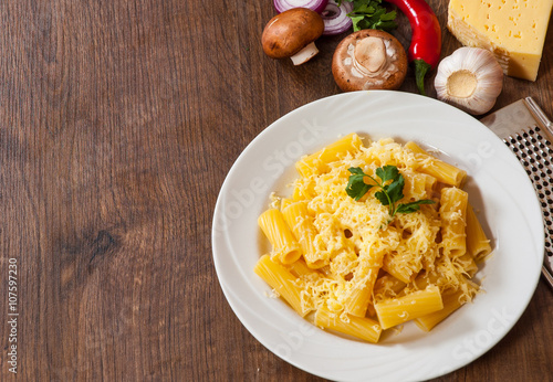 rigatoni pasta with cheese in a plate on wooden table