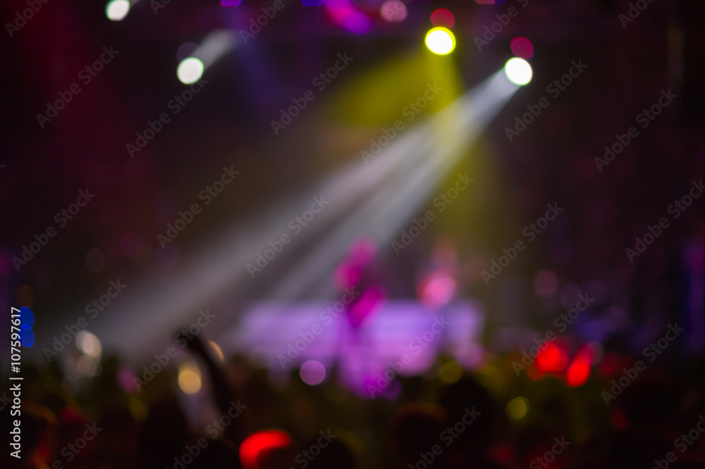 Blurred background : Club, disco DJ playing and mixing music for crowd of happy people. Nightlife, concert lights, flares
