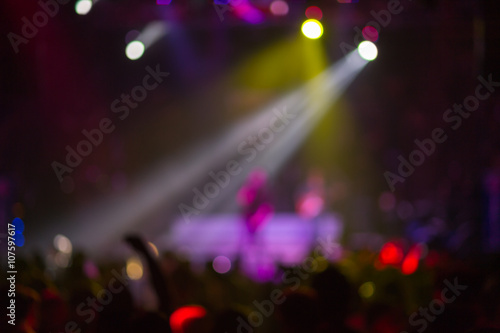 Blurred background : Club, disco DJ playing and mixing music for crowd of happy people. Nightlife, concert lights, flares 