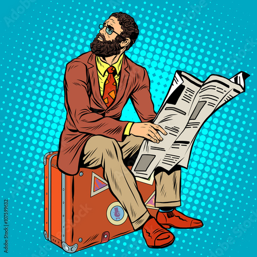 Bearded hipster traveler reading a newspaper