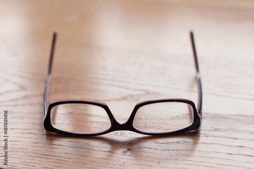 Close up of eyeglasses on the wooden office desk, blurred background Close up of eyeglasses on the wooden office desk, blurred background