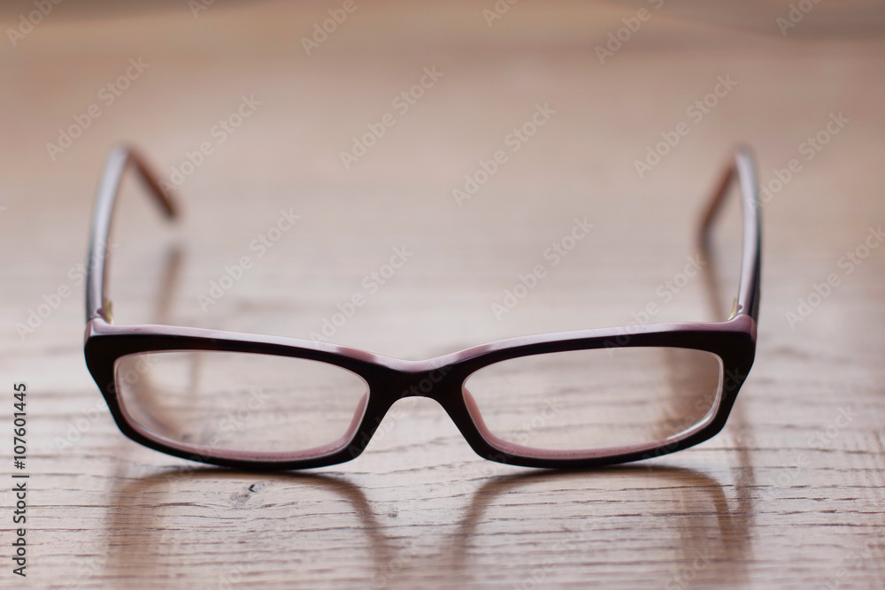 Close up of eyeglasses on the wooden office desk, blurred background Close up of eyeglasses on the wooden office desk, blurred background