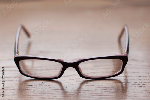 Close up of eyeglasses on the wooden office desk, blurred background