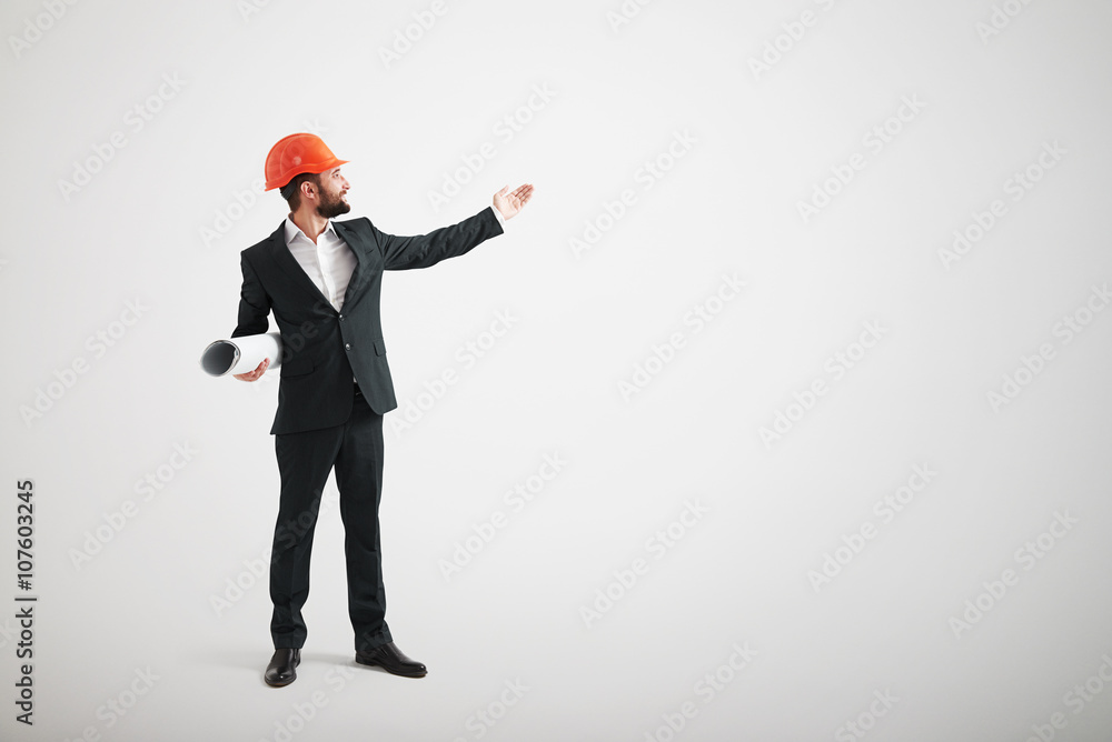 Man in formal wear and a construction helmet point his hand towa Man in formal wear and a construction helmet point his hand towa
