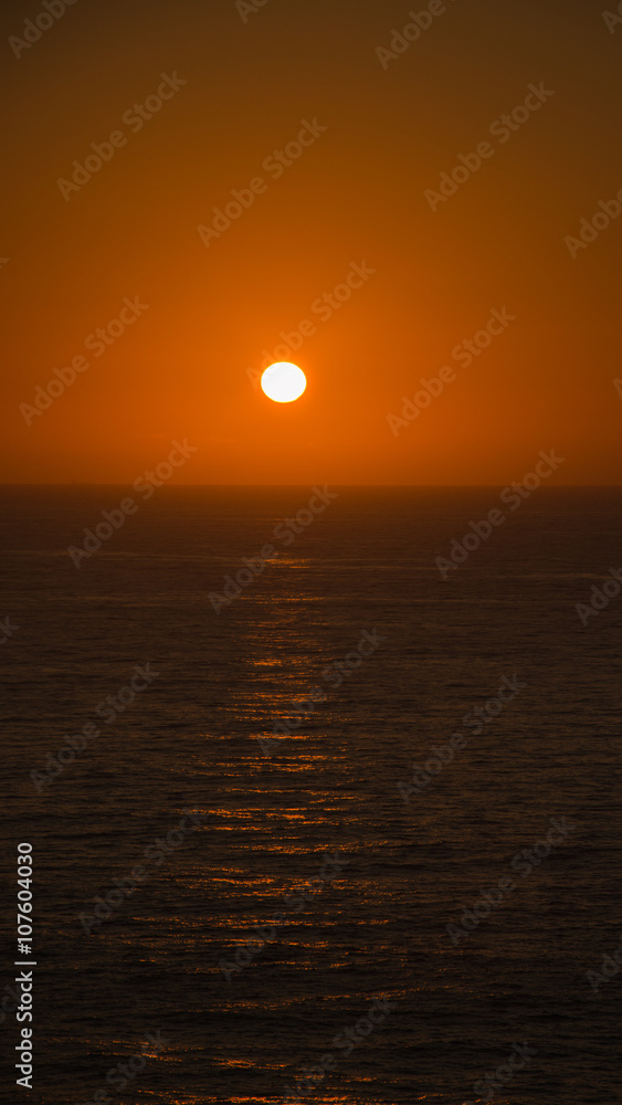 scenic sunset over the sea, sun turns red few moments before disappearing behind the water horizon