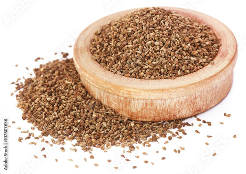 Ajwain seeds in a wooden bowl over white background