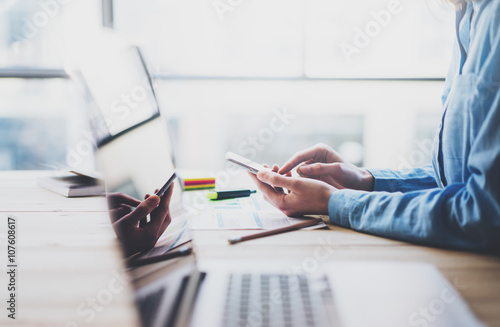 Working process photo. Account manager working wood table with new business project. Typing contemporary smartphone screen. Modern notebook reflections screen.Horizontal.Film effect,blurred