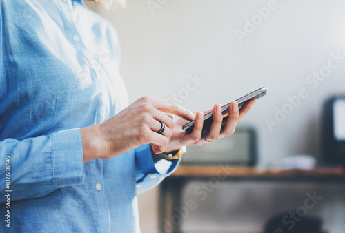 Photo business woman wearing jeans shirt  touching smartphone screen. Modern loft office. Blurred background. Horizontal mockup. Film effect