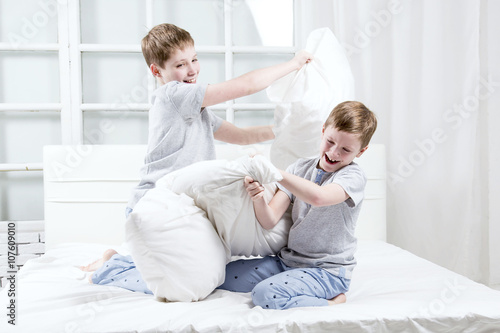 Young children playing on the bed. Pillow fight