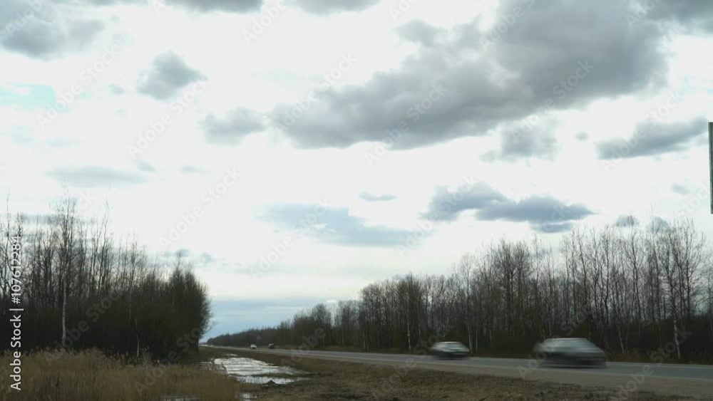 Cars speeding on highway. Clouds float across sky Cars speeding on highway. Clouds float across sky