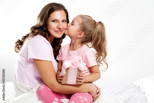 Happy family. Mother and daughter with pink gift box. Daughter kissing mom. Mother's day 