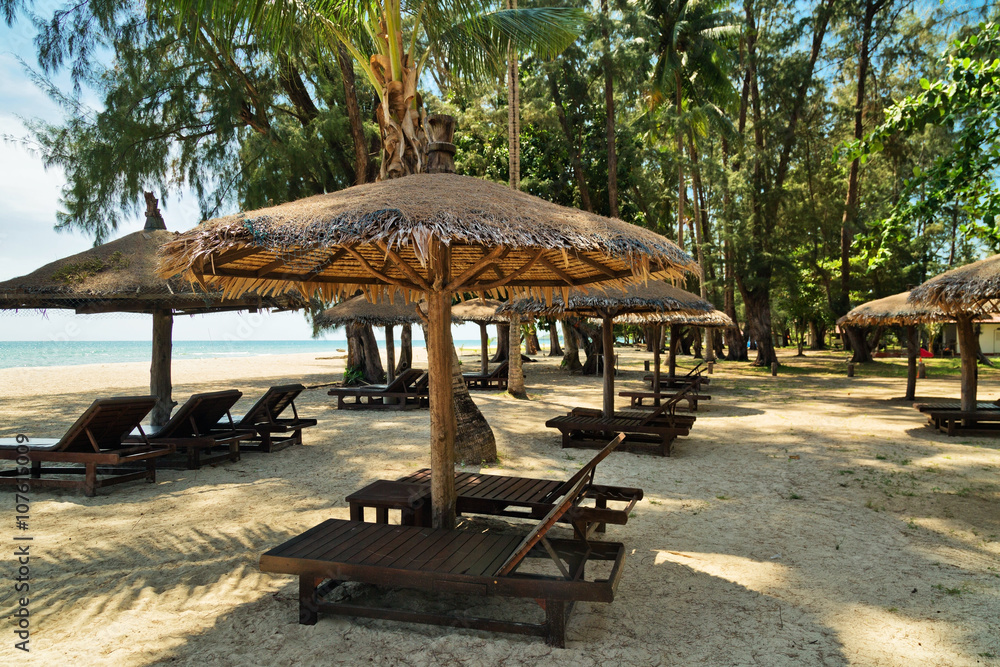Wooden chairs and umbrellas on white sand beach