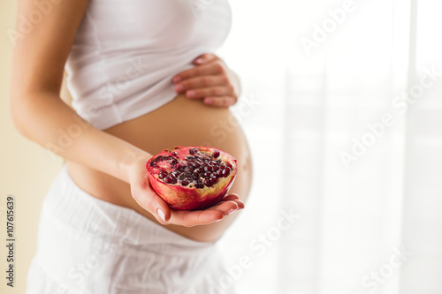 Pregnant woman holding pomegranate