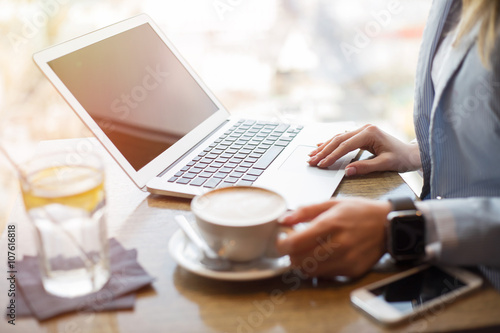 Woman drinking coffee and working on laptop