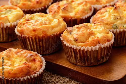 Homemade muffins with chicken and cheese on brown wooden board.