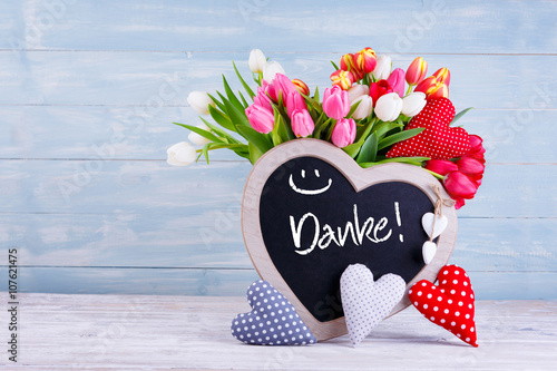 Muttertag - Bunter Blumenstrauß, Herzen und Tafel mit Aufschrift DANKE vor Holzhintergrund