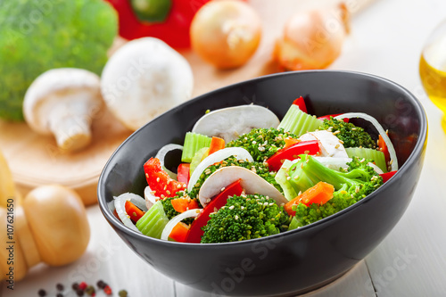 Bowl of healthy vegetarian food. Salad with broccoli, onion, mushroom, carrot and pepper.