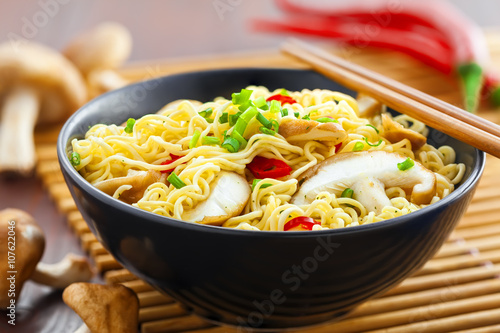 Bowl of instant noodles with shiitake mushrooms, pepper and onion on table, Asian food