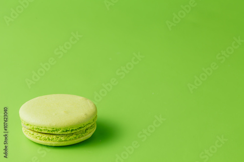 One macaroon on green background