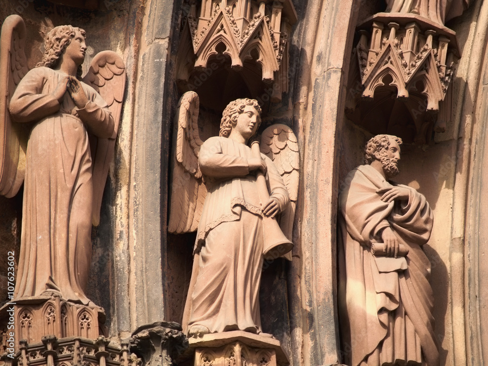 Close up of three statues engraved on Strasbourg cathedral.