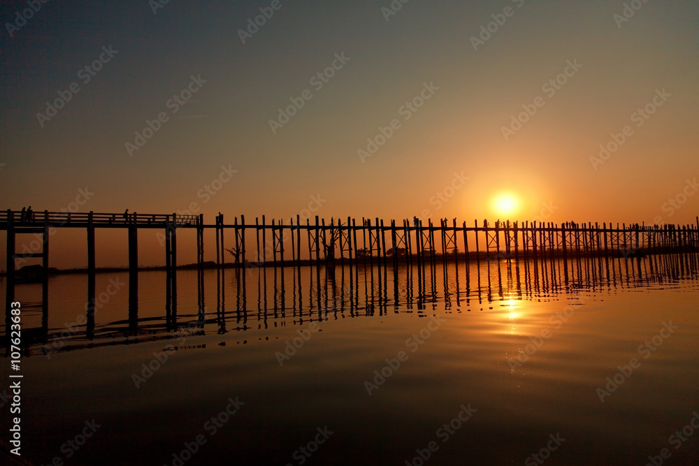 U Bein Bridge at sunset with people crossing Ayeyarwady River, Mandalay, Myanmar. Wide angle shot