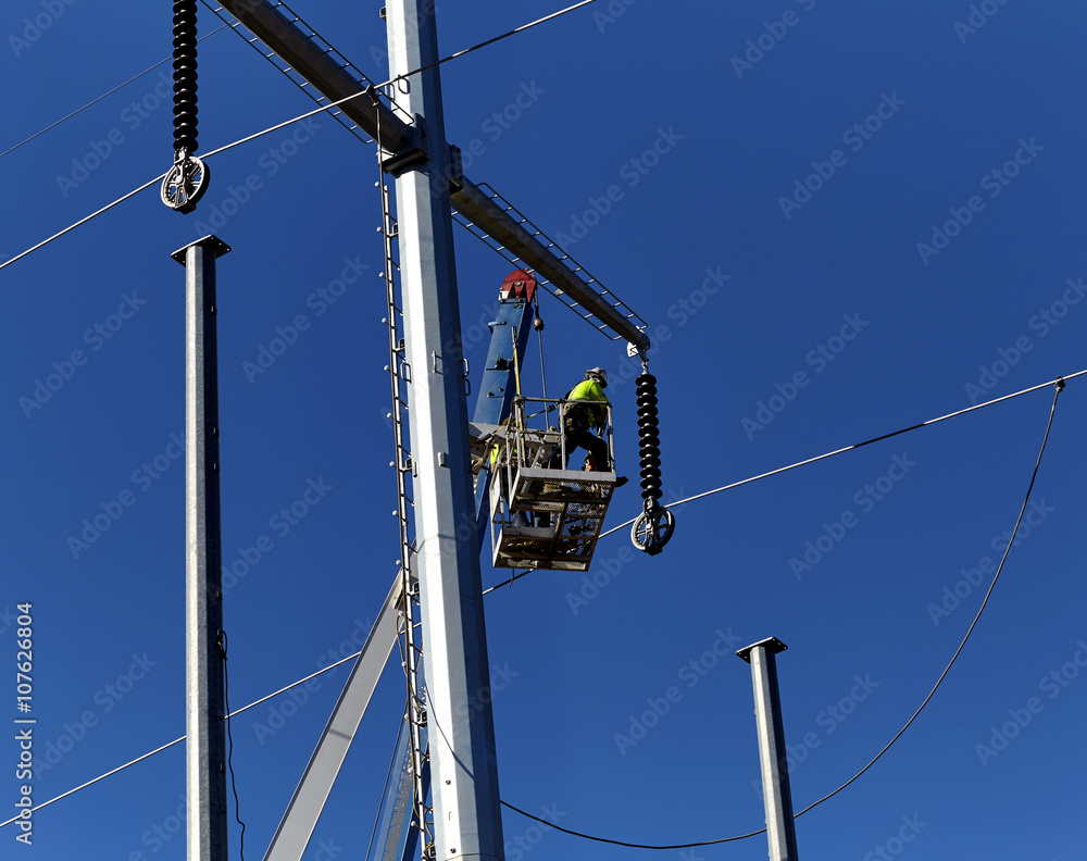 Utility worker in a boom crane basket servicing utility poles Utility worker in a boom crane basket servicing utility poles