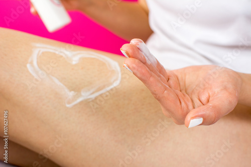Woman applying lotion on her leg