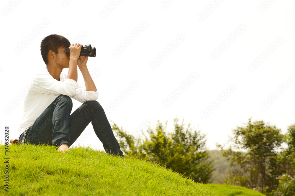 Asian young boy lying mound seeking binoculars. . Asian young boy lying mound seeking binoculars. .