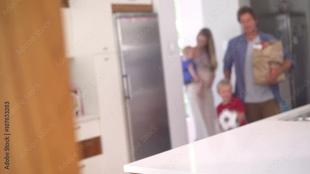 Family with Infant Daughter Unpacking Groceries in Kitchen