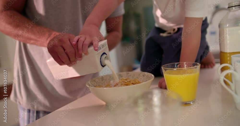 Father and son preparing cornflakes in a bowl with milk Father and son preparing cornflakes in a bowl with milk