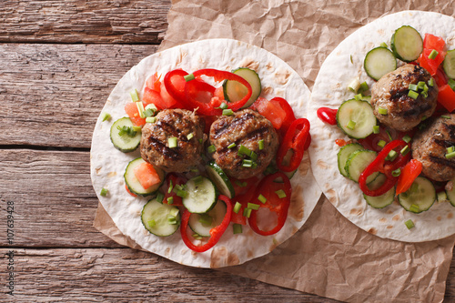Grilled meat balls with fresh vegetables on a flat bread. Horizontal top view
