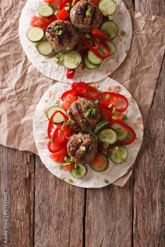 Grilled meat balls with fresh vegetables on a flat bread. Vertical top view
